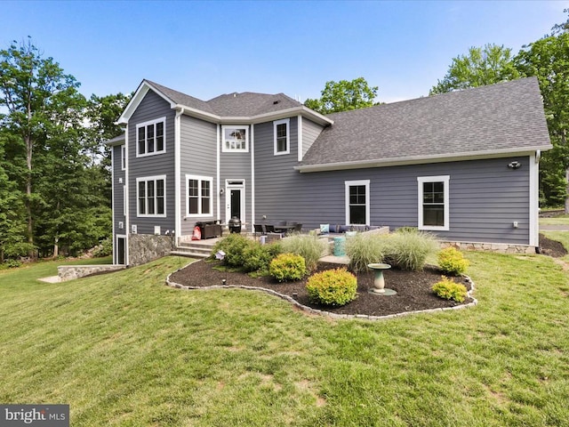 rear view of property featuring a lawn and roof with shingles