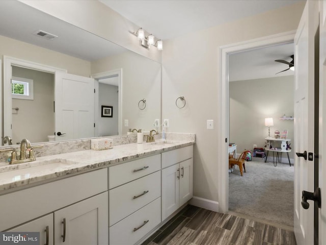 full bath with double vanity, wood finished floors, baseboards, and a ceiling fan