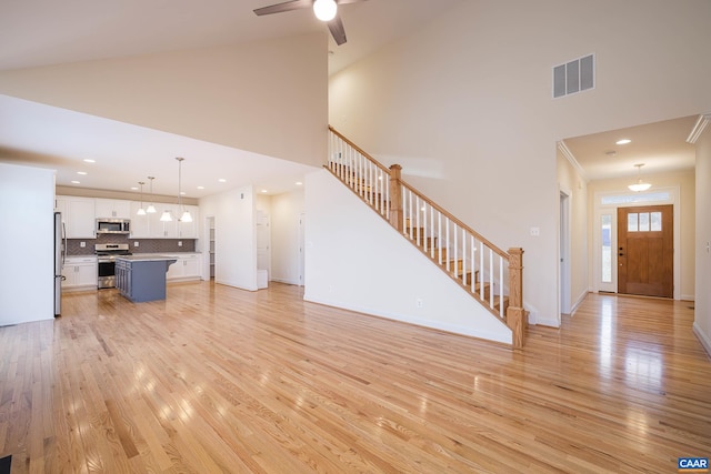 212 Bartholomew Pl, Stanardsville, VA 22973 - unfurnished living room featuring light wood-style floors, visible vents, a high ceiling, and stairway