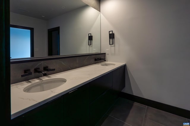 bathroom featuring a sink, double vanity, baseboards, and tile patterned floors