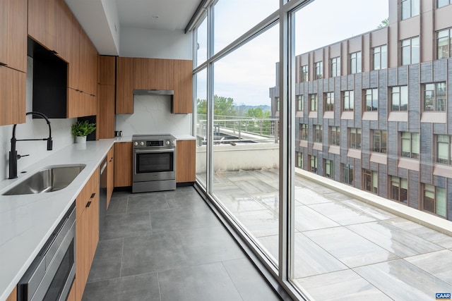 kitchen with brown cabinets, plenty of natural light, appliances with stainless steel finishes, and a sink