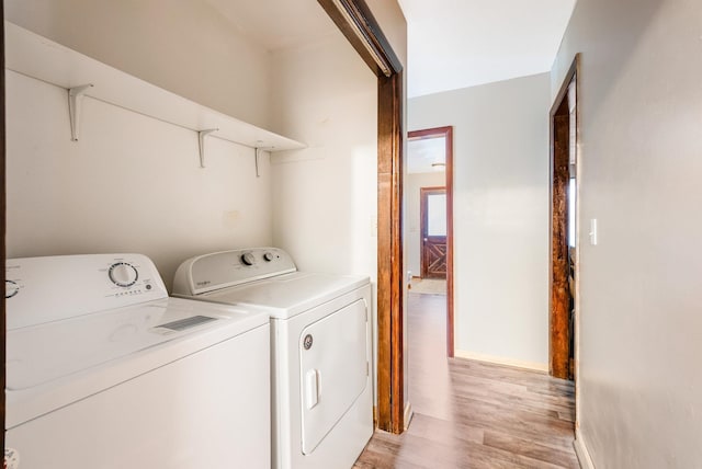 washroom with washing machine and dryer and light hardwood / wood-style floors