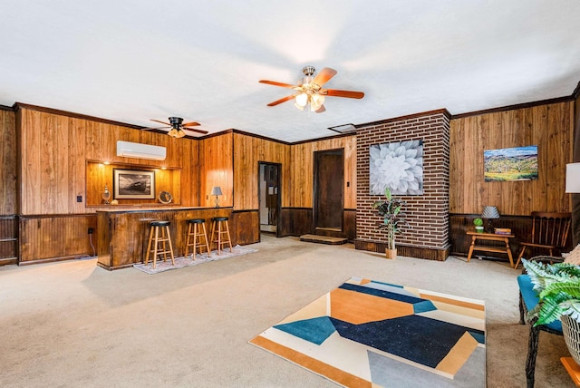 carpeted living room with bar, crown molding, a wall mounted AC, wooden walls, and ceiling fan