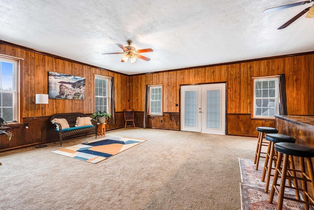 carpeted living room featuring a textured ceiling, ceiling fan, and wood walls