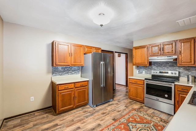 kitchen with stainless steel appliances, light wood-type flooring, and decorative backsplash