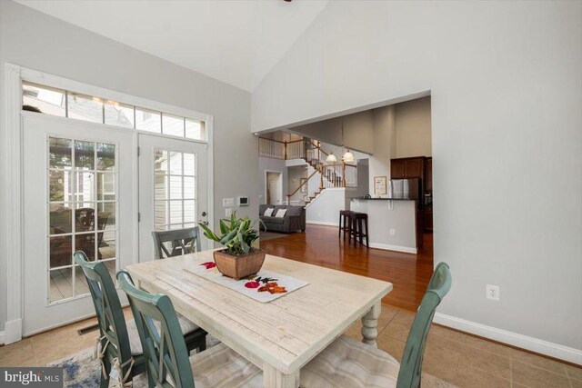 - dining room featuring high vaulted ceiling, stairs, baseboards, and a chandelier