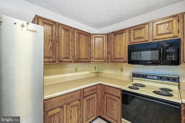3716 Martin Kings Rd, Charlottesville, VA 22902 - kitchen with electric range, black microwave, fridge, brown cabinetry, and a textured ceiling