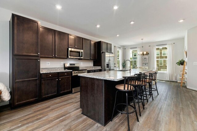 301 Willowshire Ct, Waynesboro, VA 22980 - kitchen with appliances with stainless steel finishes, light wood-style flooring, a center island with sink, a breakfast bar, and dark brown cabinets
