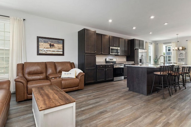301 Willowshire Ct, Waynesboro, VA 22980 - kitchen with appliances with stainless steel finishes, open floor plan, wood finished floors, a kitchen bar, and dark brown cabinetry