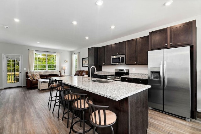 301 Willowshire Ct, Waynesboro, VA 22980 - kitchen featuring appliances with stainless steel finishes, dark brown cabinets, light wood-style flooring, a kitchen island with sink, and a kitchen breakfast bar
