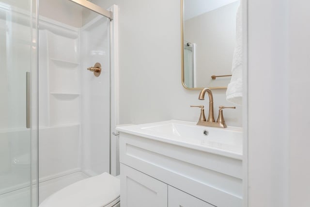 bathroom with an enclosed shower, vanity, and toilet