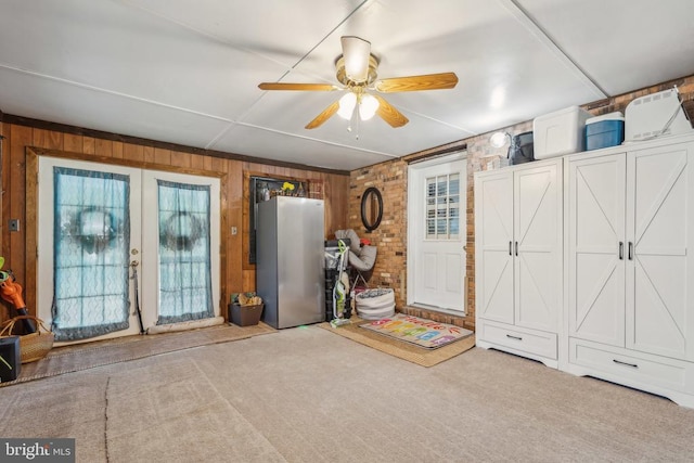  - entrance foyer featuring wooden walls, carpet floors, ceiling fan, and french doors
