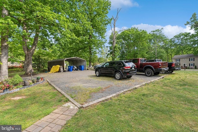  - view of vehicle parking featuring gravel driveway, a detached carport, and view of scattered trees