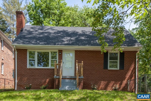 view of front facade featuring a chimney, brick siding, and a shingled roof