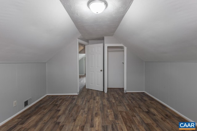 additional living space with wood finished floors, baseboards, vaulted ceiling, and wood walls