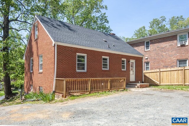 back of property with brick siding, fence, a shingled roof, and cooling unit