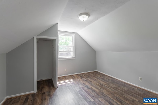 additional living space with wood finished floors, vaulted ceiling, and baseboards