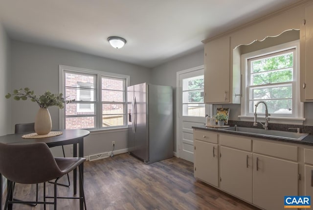 kitchen with stainless steel fridge with ice dispenser, a sink, dark wood finished floors, and dark countertops