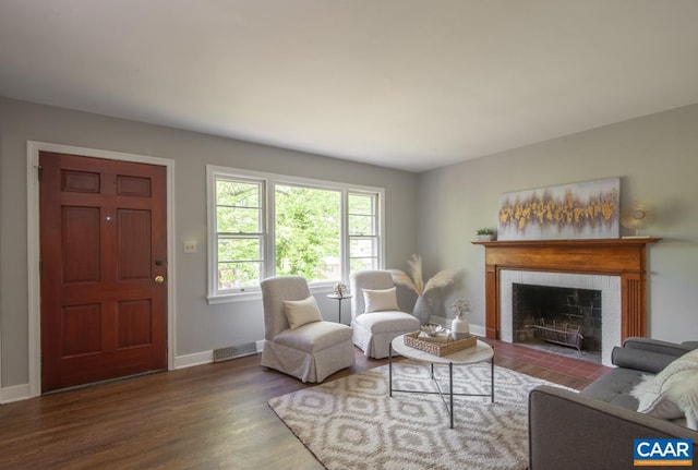 living area with baseboards, wood finished floors, and a brick fireplace