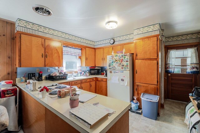 205 Lewis Ave, Elkton, VA 22827 - kitchen featuring freestanding refrigerator, light countertops, a peninsula, brown cabinets, and black microwave