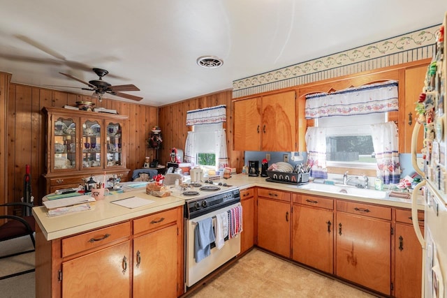 205 Lewis Ave, Elkton, VA 22827 - kitchen with light countertops, white range with electric stovetop, ceiling fan, wood walls, and brown cabinets