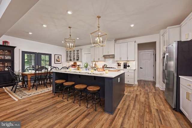 - kitchen with freestanding refrigerator, wood finished floors, light countertops, a breakfast bar, and a chandelier