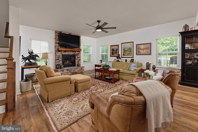  - living room with a ceiling fan, stairs, a stone fireplace, and wood finished floors