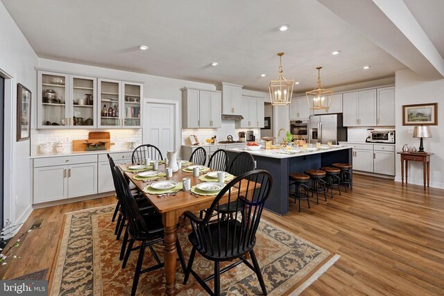  - dining area with a chandelier, wood finished floors, and recessed lighting