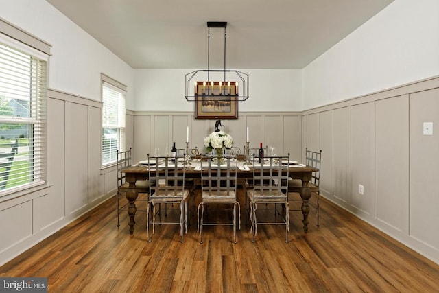 - dining area with a decorative wall, wood finished floors, and a wainscoted wall