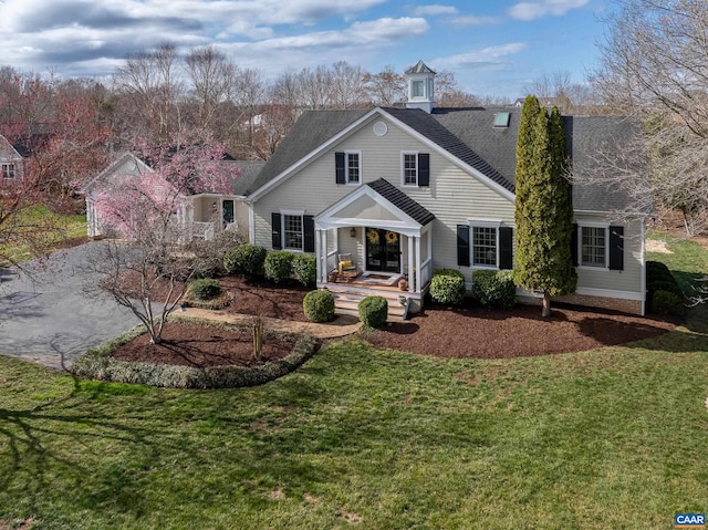 view of front of property with a porch, roof with shingles, and a front lawn