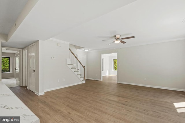 1132 Amber Ridge Rd, Charlottesville, VA 22901 - unfurnished living room with stairs, healthy amount of natural light, a ceiling fan, light wood-type flooring, and crown molding