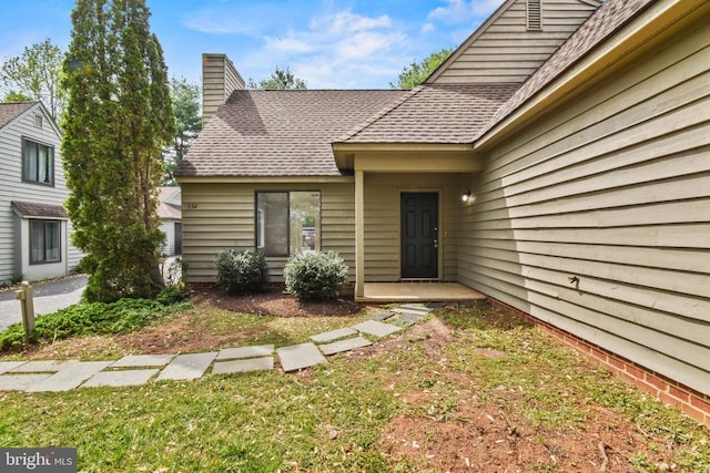1132 Amber Ridge Rd, Charlottesville, VA 22901 - view of exterior entry featuring roof with shingles, a chimney, and a yard