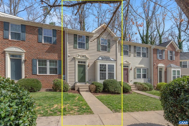 townhome / multi-family property with a front lawn and brick siding