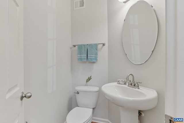 bathroom featuring a sink, toilet, baseboards, and visible vents