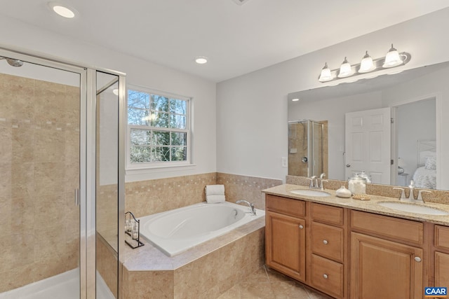 full bath with a sink, double vanity, a stall shower, and a garden tub