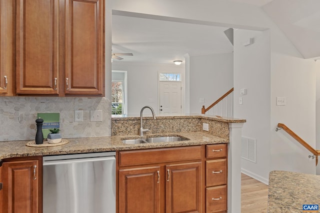 kitchen featuring light stone countertops, stainless steel dishwasher, light wood finished floors, visible vents, and a sink