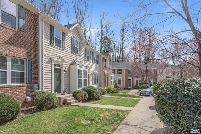 exterior space with brick siding, a residential view, and a front yard
