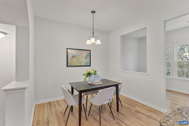 dining area with baseboards, light wood-style flooring, and a chandelier