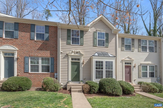 view of property with a front lawn and brick siding