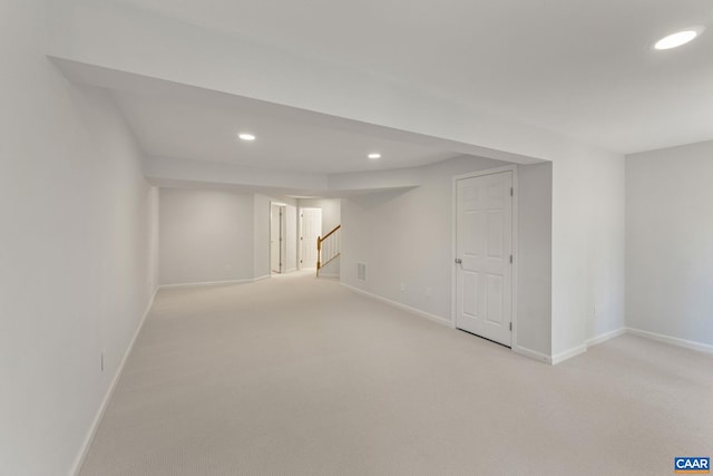 finished below grade area with stairway, light colored carpet, baseboards, and recessed lighting