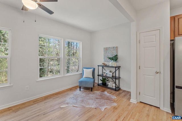 sitting room featuring baseboards, light wood-style floors, and ceiling fan