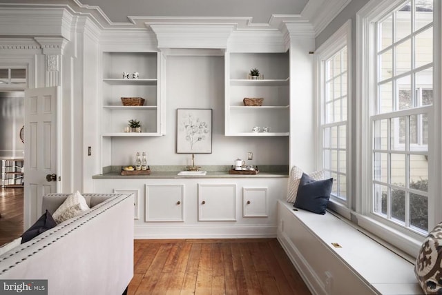  - bar area with crown molding, hardwood / wood-style floors, and built in shelves