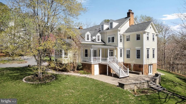  - rear view of house featuring stairway, a yard, a chimney, and covered porch
