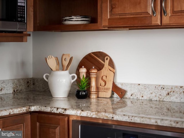  - detailed view of black microwave, beverage cooler, light stone countertops, and brown cabinetry