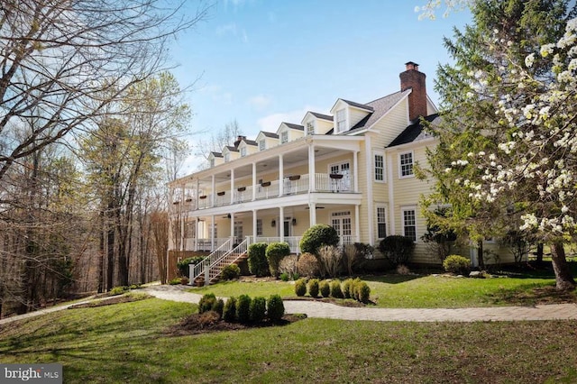  - view of front facade with covered porch, a front yard, a chimney, and stairs