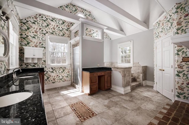  - bathroom with wallpapered walls, vaulted ceiling, double vanity, and a stall shower