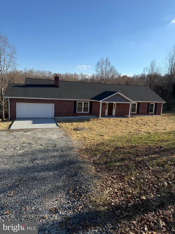 19196 Ferguson Ln, Jeffersonton, VA 22724 - view of front facade featuring gravel driveway, a chimney, brick siding, and an attached garage