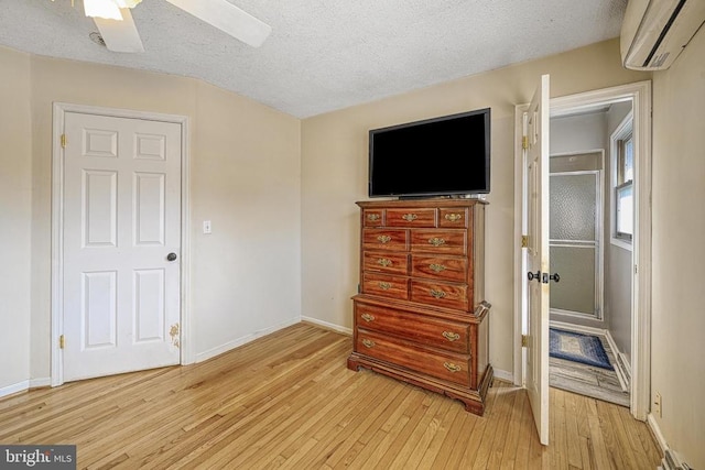 119 Birchside Cir, Locust Grove, VA 22508 - bedroom featuring a wall unit AC, light wood-type flooring, a textured ceiling, baseboards, and a ceiling fan