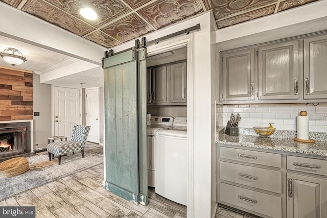 119 Birchside Cir, Locust Grove, VA 22508 - clothes washing area with washing machine and clothes dryer, wooden walls, light wood-type flooring, a barn door, and a fireplace