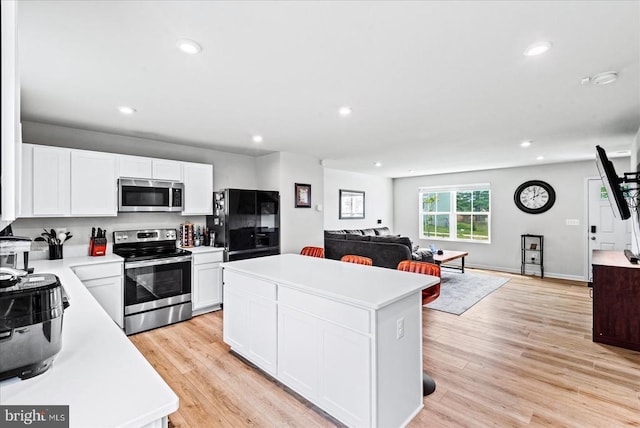 kitchen with appliances with stainless steel finishes, open floor plan, a kitchen island, recessed lighting, and light countertops